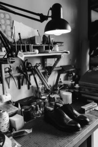 Explore a traditional shoemaker's workshop filled with tools and crafted shoes, captured in classic black and white.