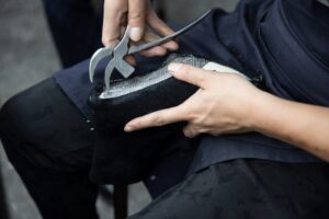 Close-up of a craftsman repairing a leather shoe with a cobbler's plier.