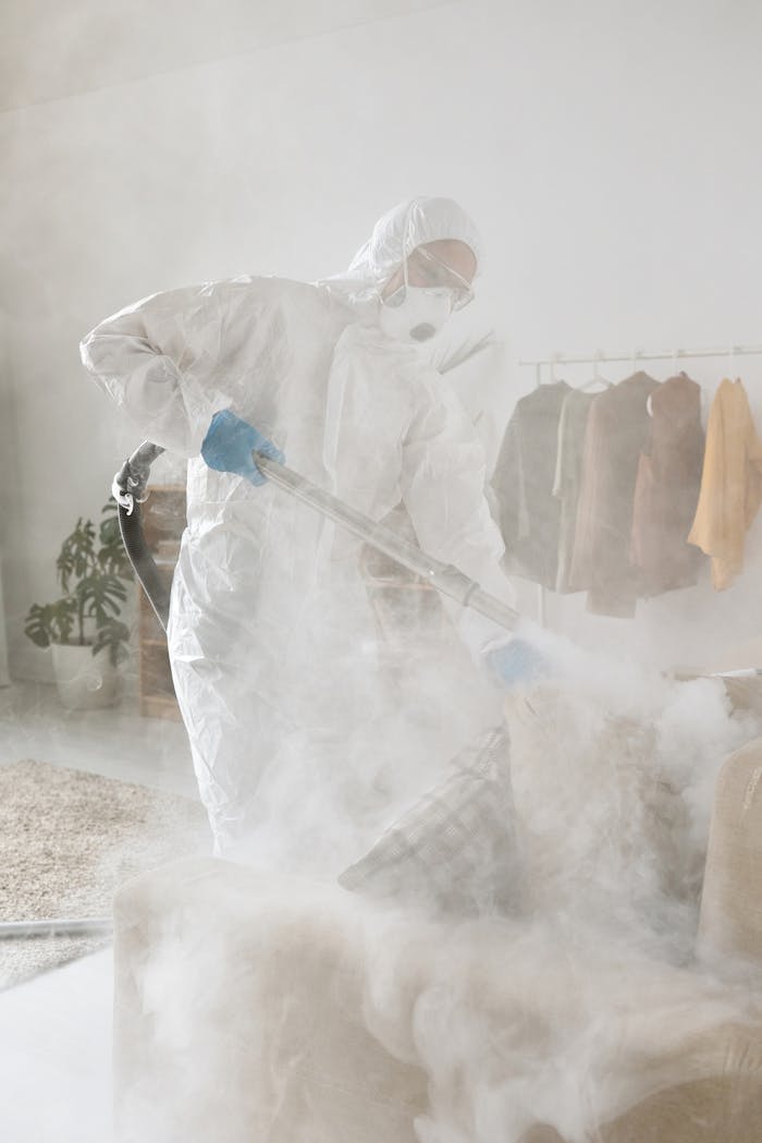 Person in protective suit fogging indoors, enhancing cleanliness.