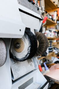 Detailed view of industrial shoe polishing machine with brushes in a workshop setting.